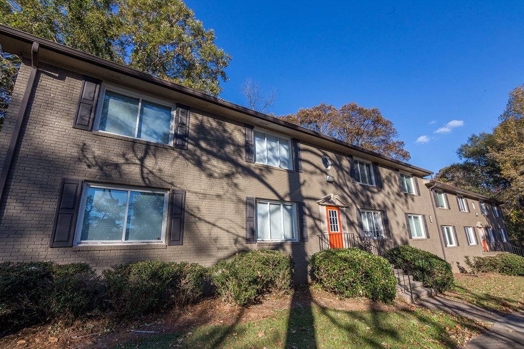 a brick apartment building with an orange door on a sunny day at Broadway at East Atlanta, Atlanta, GA